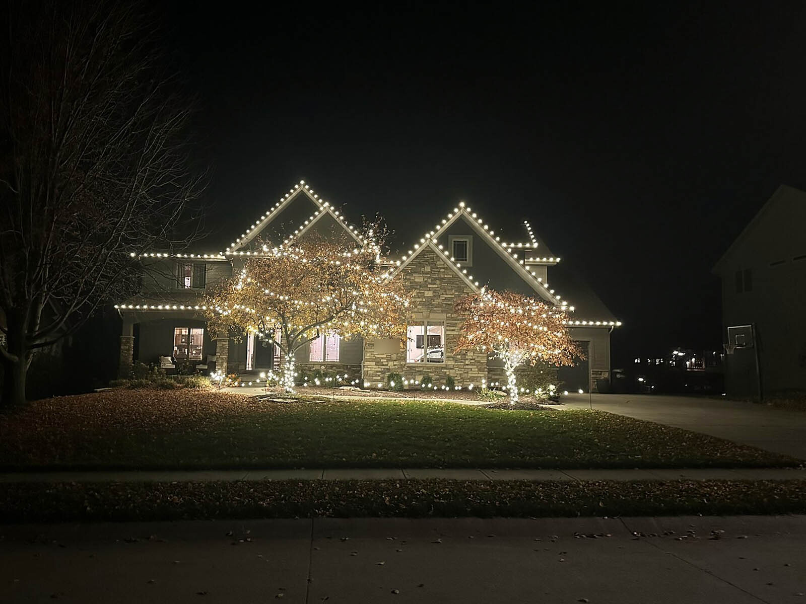 Large two-story home with multiple gables outlined in christmas lights at dusk