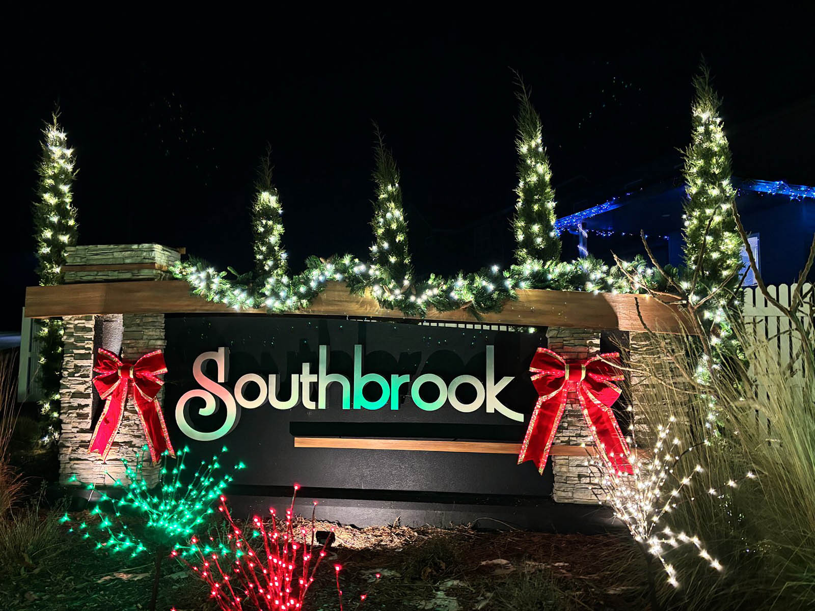Southbrook neighborhood entrance monument and trees wrapped in warm holiday lighting